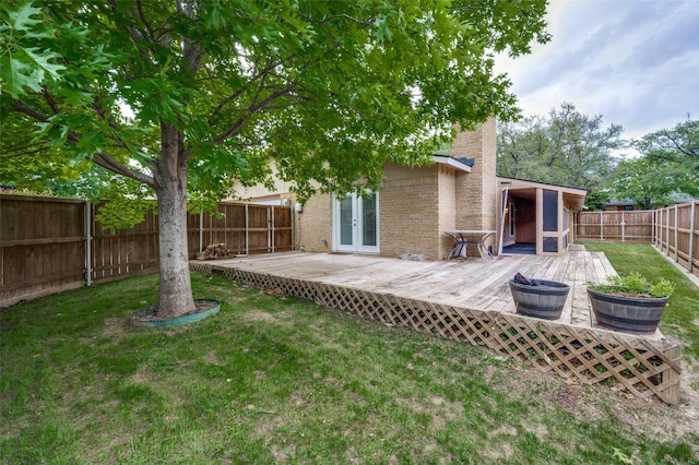 rear view of property featuring french doors, a yard, a fenced backyard, and a deck