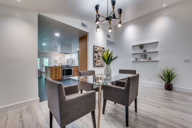 dining room with visible vents, light wood-style floors, baseboards, and an inviting chandelier