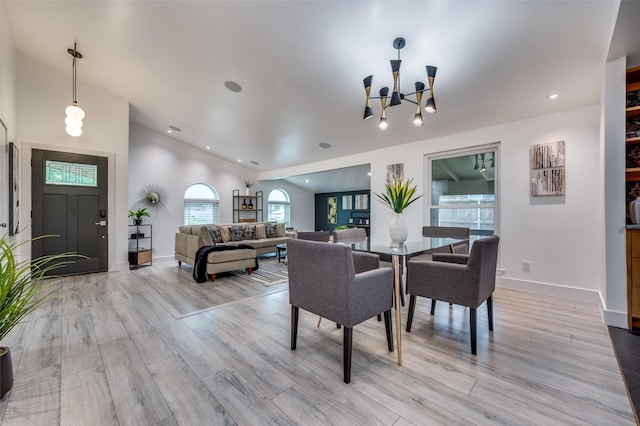 dining area featuring an inviting chandelier, lofted ceiling, light wood-style floors, baseboards, and recessed lighting