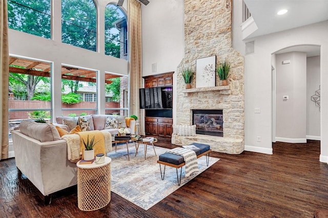 living room featuring baseboards, arched walkways, a towering ceiling, and wood finished floors