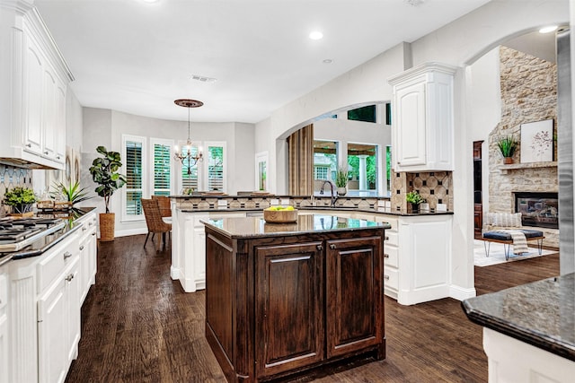 kitchen featuring visible vents, tasteful backsplash, a sink, white cabinetry, and dark wood-type flooring