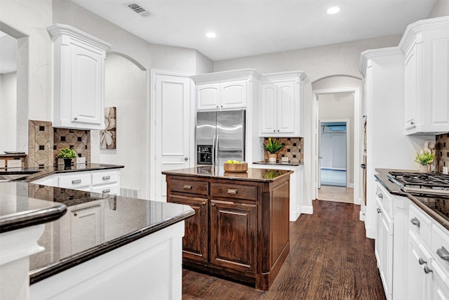 kitchen with appliances with stainless steel finishes, arched walkways, white cabinetry, and visible vents