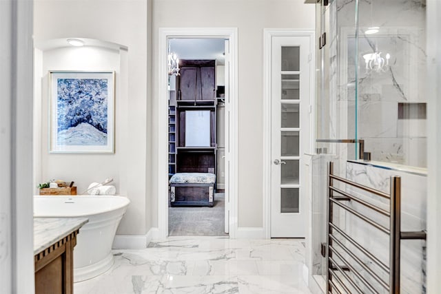 bathroom featuring a freestanding bath, a marble finish shower, baseboards, and marble finish floor