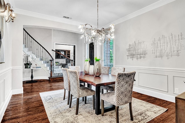 dining space featuring visible vents, crown molding, wood finished floors, a decorative wall, and stairs