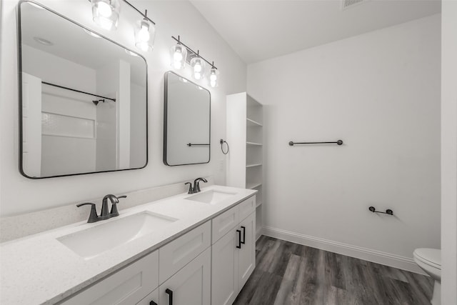 bathroom featuring baseboards, a sink, wood finished floors, and toilet
