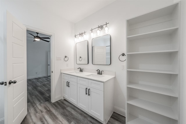 full bath with double vanity, a ceiling fan, a sink, and wood finished floors