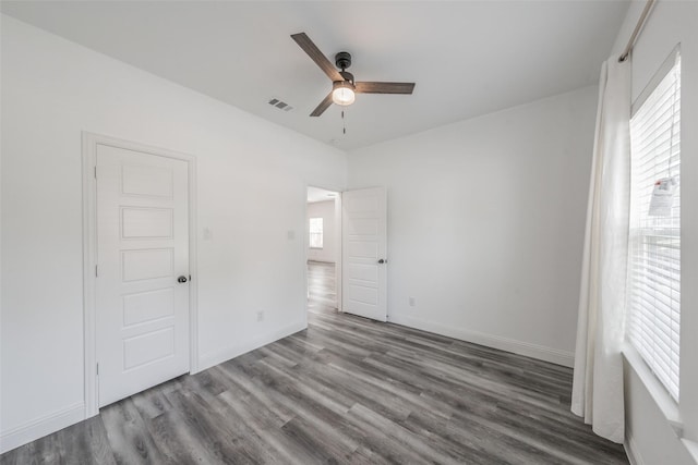unfurnished bedroom featuring a ceiling fan, baseboards, visible vents, and wood finished floors
