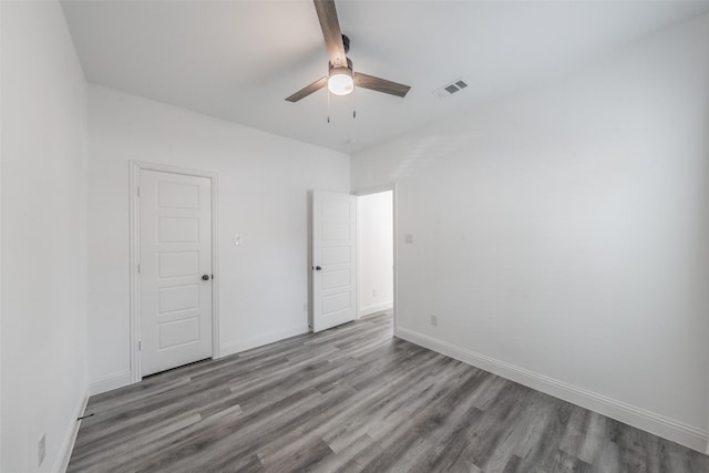 unfurnished bedroom featuring a ceiling fan, baseboards, visible vents, and wood finished floors