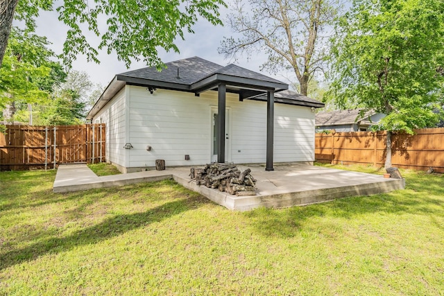 rear view of house with a fenced backyard, a patio area, a yard, and a shingled roof