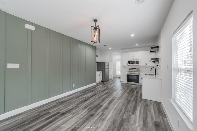 unfurnished living room with a wall mounted air conditioner, a sink, baseboards, recessed lighting, and dark wood-type flooring