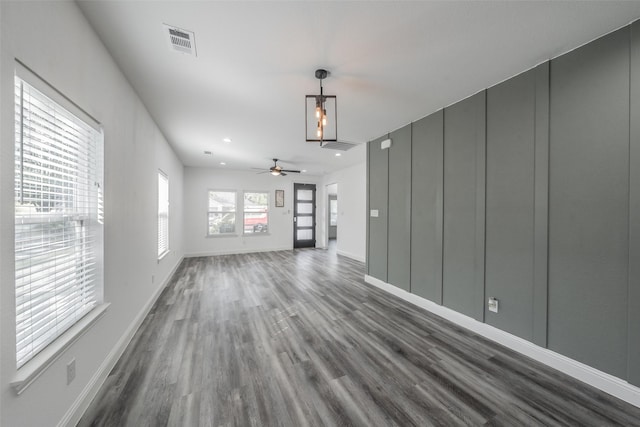 unfurnished living room featuring visible vents, baseboards, dark wood-type flooring, and ceiling fan