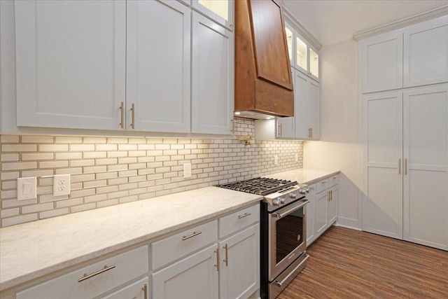 kitchen featuring high end stainless steel range, glass insert cabinets, white cabinetry, tasteful backsplash, and light stone counters