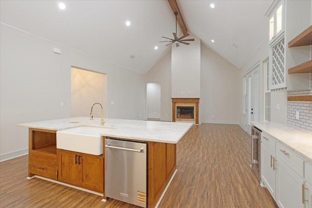kitchen with stainless steel dishwasher, open shelves, a sink, and beam ceiling