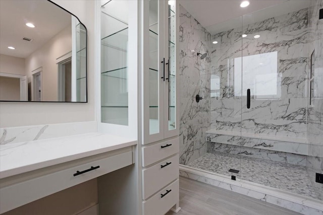 bathroom with recessed lighting, a marble finish shower, visible vents, and vanity