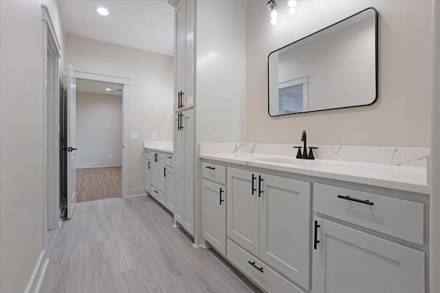 bathroom with vanity, baseboards, recessed lighting, and wood finished floors