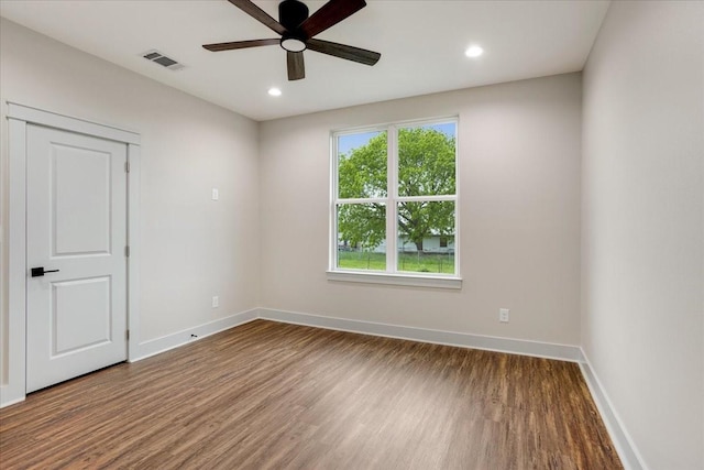 spare room featuring a ceiling fan, baseboards, visible vents, and wood finished floors