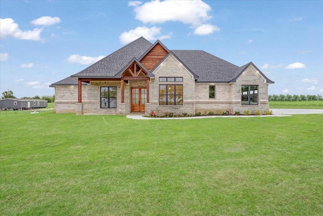 view of front of home with a front lawn, roof with shingles, french doors, and stone siding