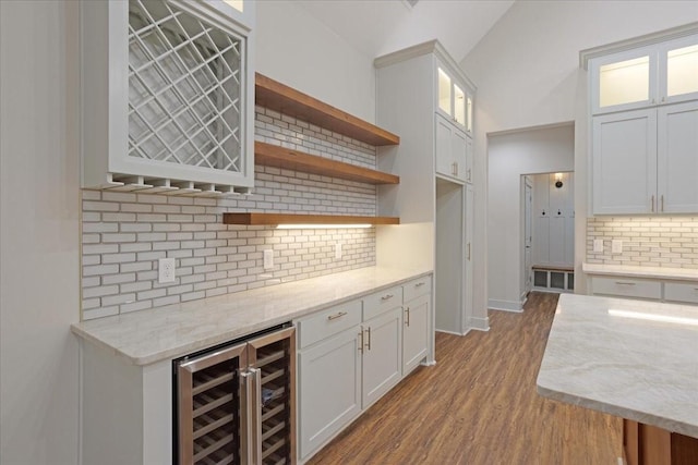 kitchen featuring white cabinetry, light stone countertops, decorative backsplash, and wine cooler