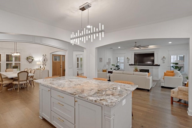 805 S Lindsay St, Gainesville, TX 76240 - kitchen featuring arched walkways, a ceiling fan, a center island, wood finished floors, and decorative light fixtures