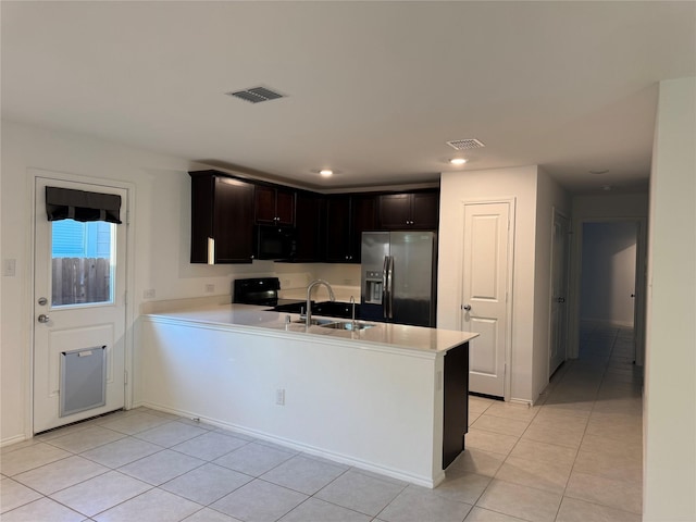 kitchen with light countertops, a peninsula, light tile patterned floors, visible vents, and black appliances