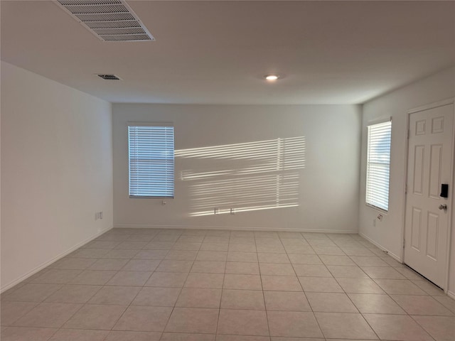 empty room with baseboards, light tile patterned flooring, and visible vents