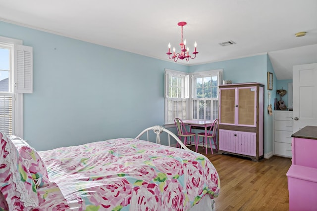 bedroom with visible vents, wood finished floors, and an inviting chandelier