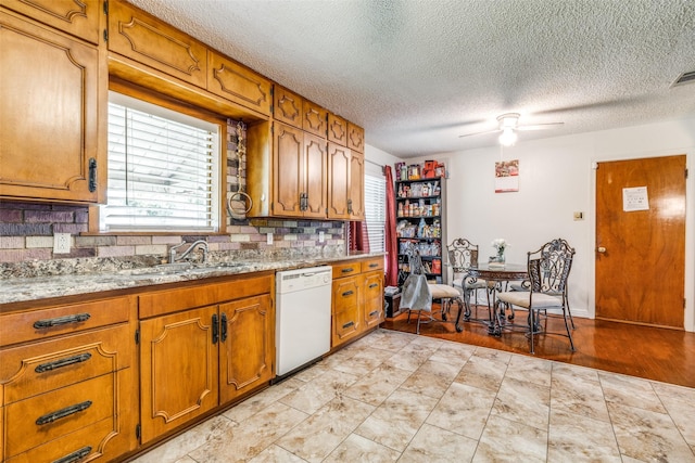 1813 Brook Hollow Dr, Fort Worth, TX 76114 - kitchen featuring brown cabinetry, dishwasher, ceiling fan, a sink, and backsplash