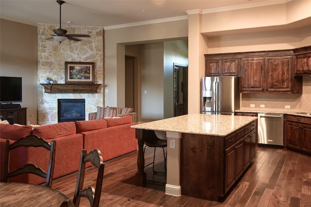 kitchen featuring a ceiling fan, dark wood-style flooring, appliances with stainless steel finishes, a fireplace, and open floor plan