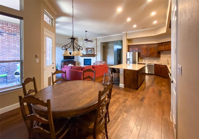 dining area with crown molding, dark wood finished floors, and a fireplace