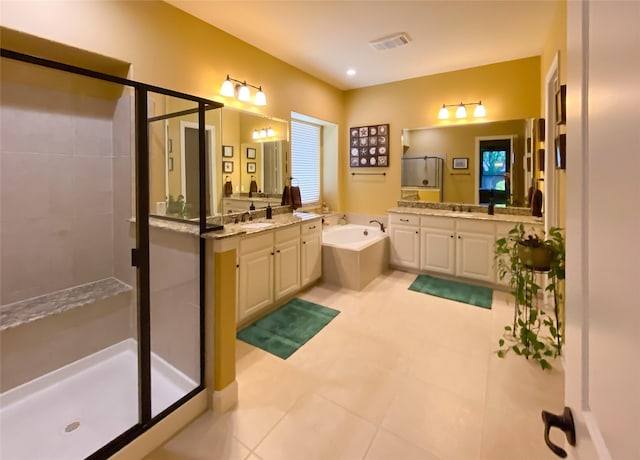 bathroom with visible vents, a garden tub, tile patterned floors, two vanities, and a stall shower
