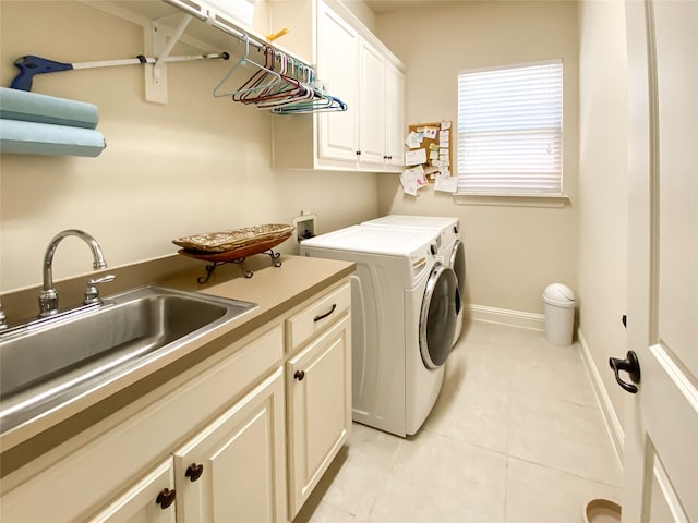 washroom with washing machine and dryer, baseboards, a sink, cabinet space, and light tile patterned floors