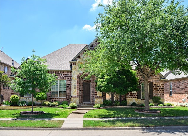 view of front of property featuring brick siding, stone siding, and a front yard