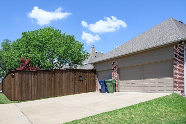 view of home's exterior featuring fence, roof with shingles, brick siding, concrete driveway, and an attached garage