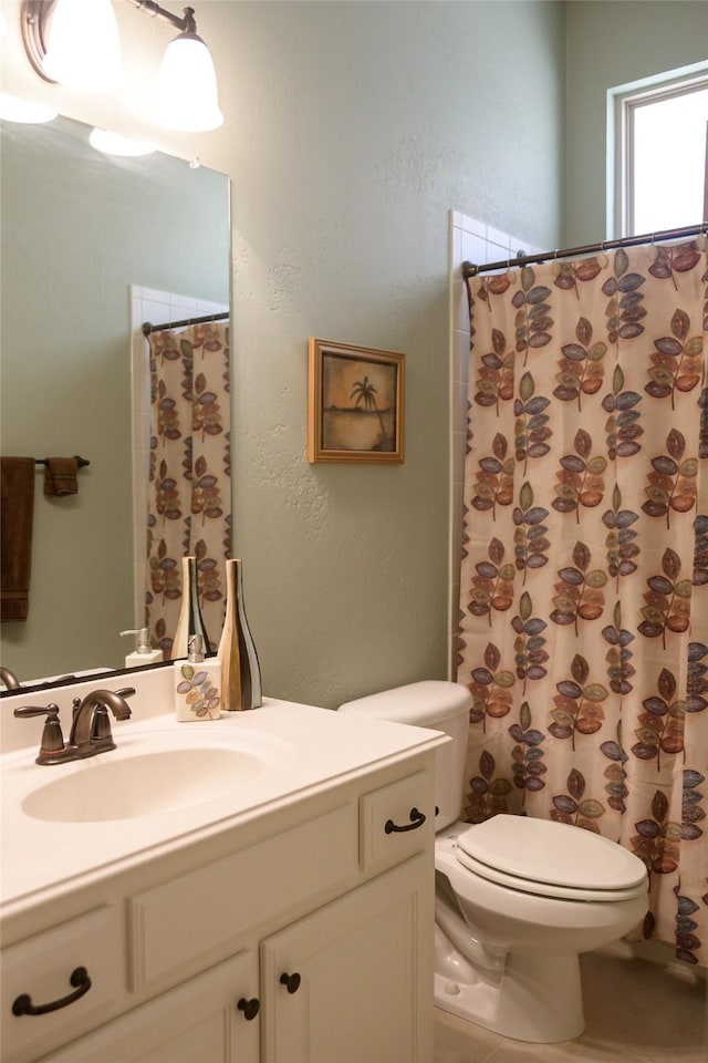 bathroom with vanity, a textured wall, and toilet