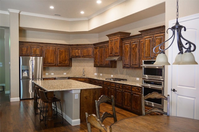kitchen featuring appliances with stainless steel finishes, a sink, a center island, backsplash, and ornamental molding