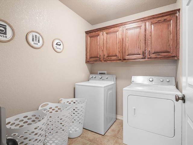 clothes washing area featuring cabinet space, light tile patterned floors, and washing machine and clothes dryer