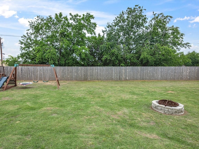 view of yard featuring a playground, a fenced backyard, and an outdoor fire pit