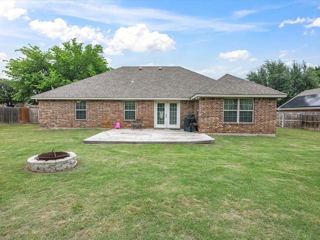 back of property featuring french doors, roof with shingles, a lawn, fence, and a fire pit