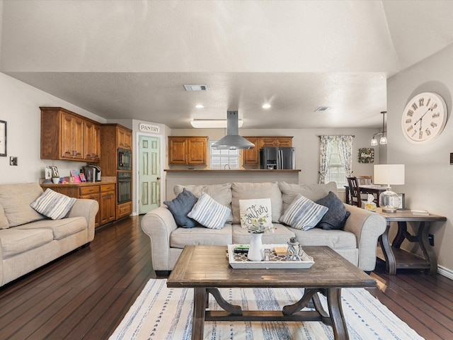 living room featuring baseboards, visible vents, a textured ceiling, and dark wood-type flooring