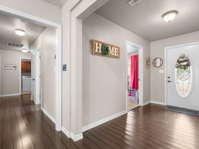 foyer with visible vents, a textured ceiling, dark wood finished floors, and washer / dryer