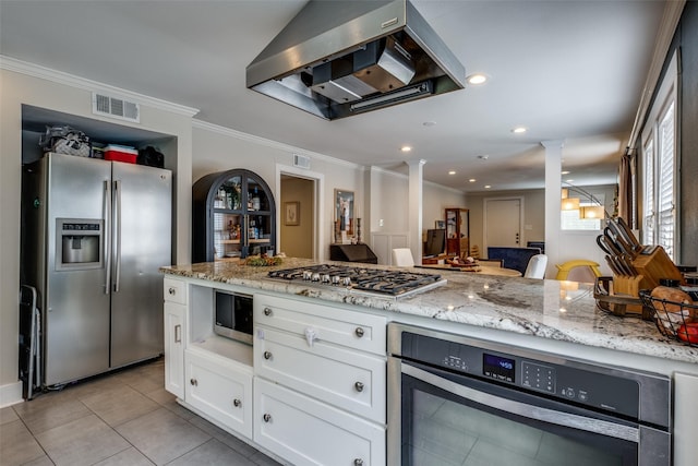 kitchen featuring decorative columns, visible vents, range hood, stainless steel appliances, and white cabinetry