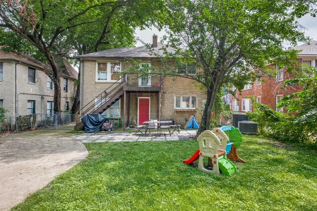 rear view of property featuring fence, brick siding, a chimney, a patio area, and a lawn