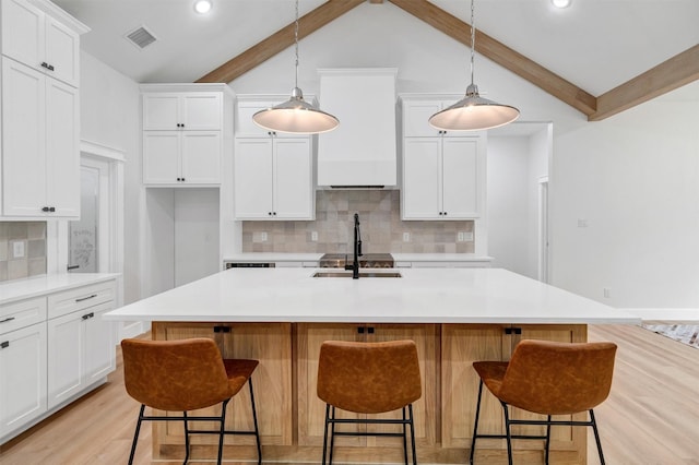 kitchen featuring decorative backsplash, vaulted ceiling with beams, white cabinetry, a sink, and light wood-style flooring