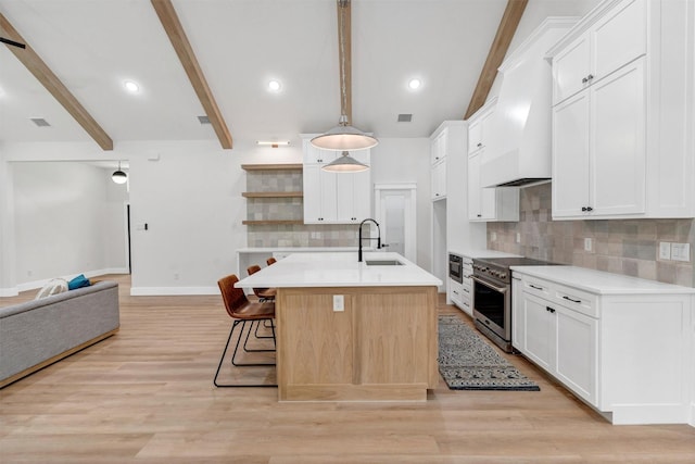 kitchen with decorative backsplash, open shelves, stainless steel stove, a sink, and open floor plan