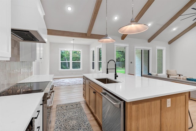 kitchen featuring a sink, stainless steel appliances, open floor plan, recessed lighting, and custom range hood