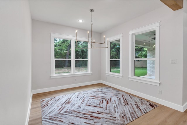 unfurnished dining area featuring baseboards, wood finished floors, and a chandelier