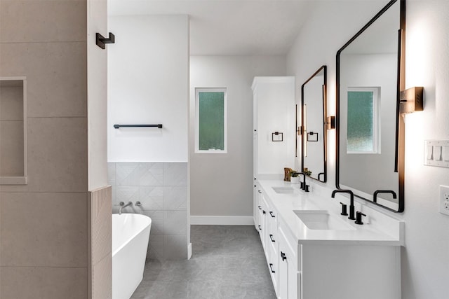 bathroom featuring a soaking tub, tile walls, a sink, and tile patterned flooring