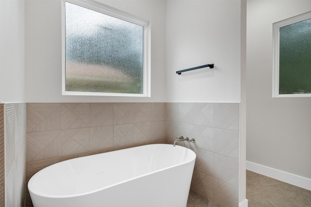 bathroom with a freestanding tub, wainscoting, and tile walls