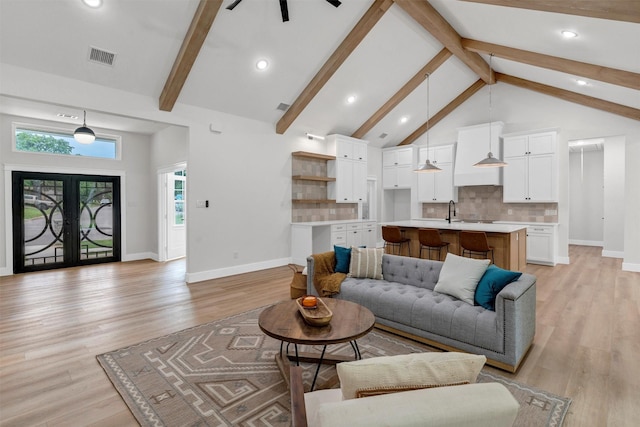 living room featuring ceiling fan, beam ceiling, and light wood-style floors
