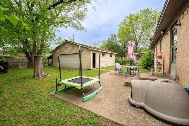 view of yard featuring fence, a detached garage, a patio area, an outbuilding, and outdoor dining space